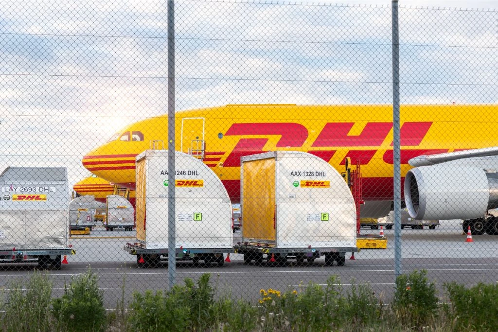 Cargo boxes with a DHL aircraft in the background.