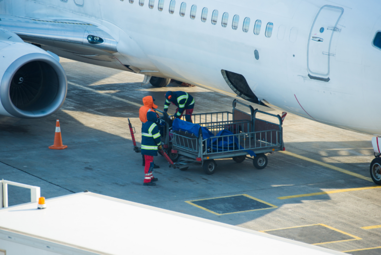 airport crew loading boxes into plane