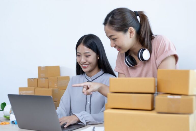 girls pointing at a laptop with packages